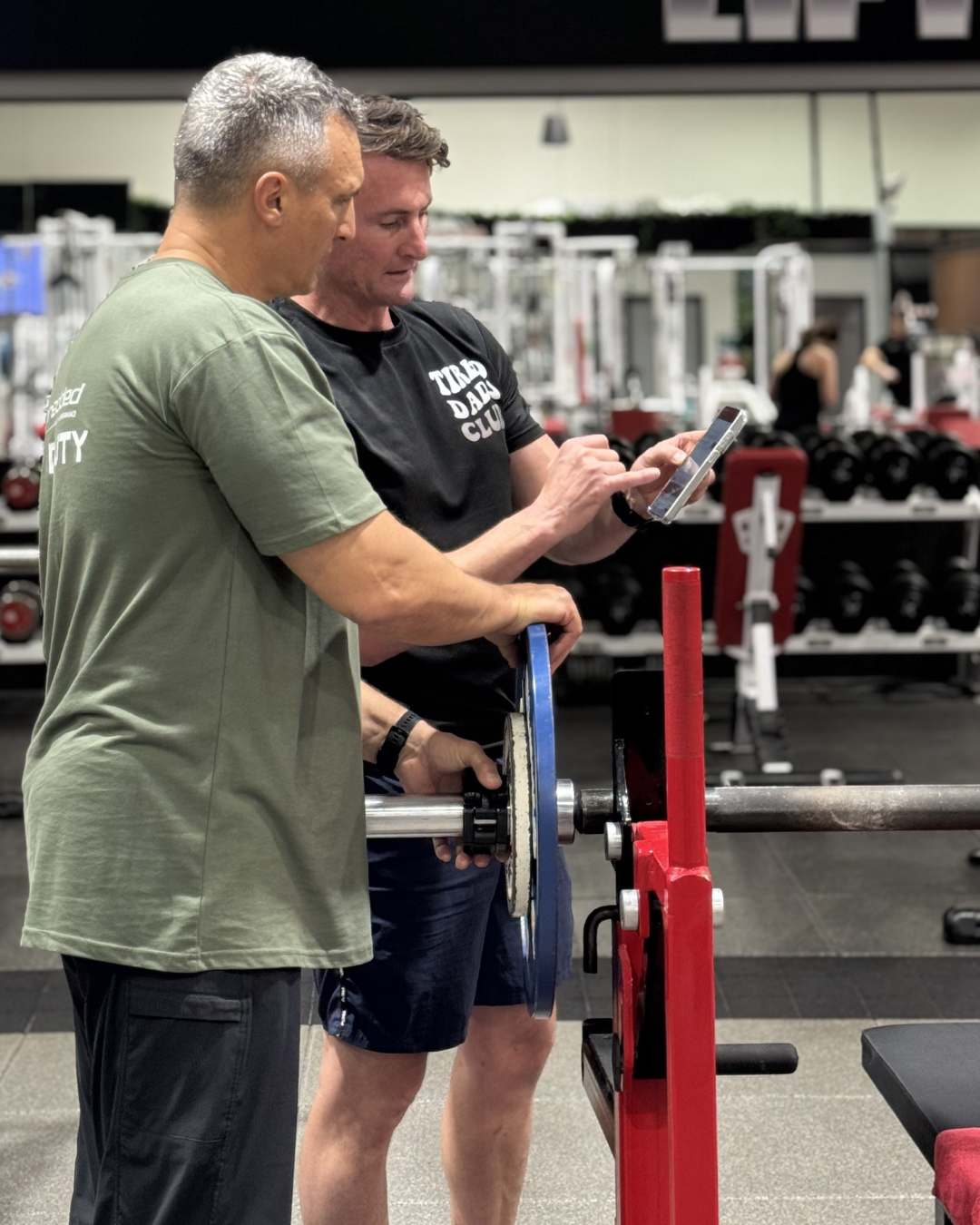 Shredded coach supporting a member through a guided strength session