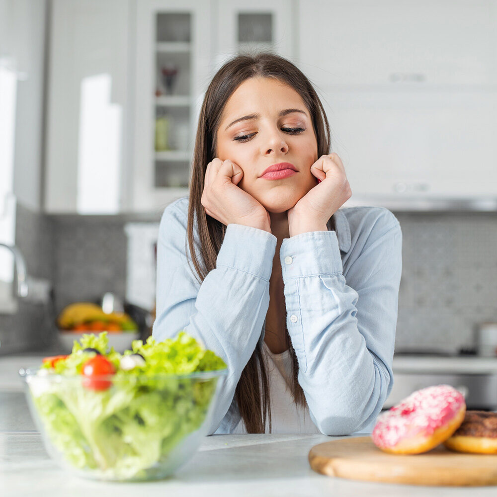 Teenage girl chooses between donuts and vegetable salad